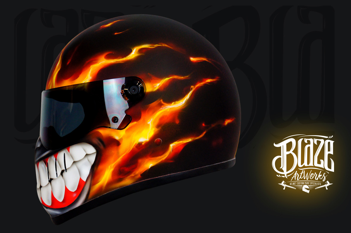 Black motorcycle helmet with realistic orange and red flame design featuring menacing white teeth with blood-red gums